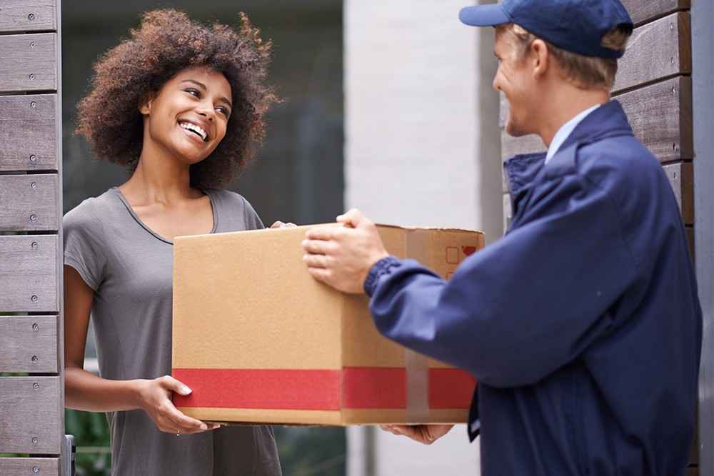 On voit un femmepasse se cartons de déménagement à un homme qui est en faite un livreur 